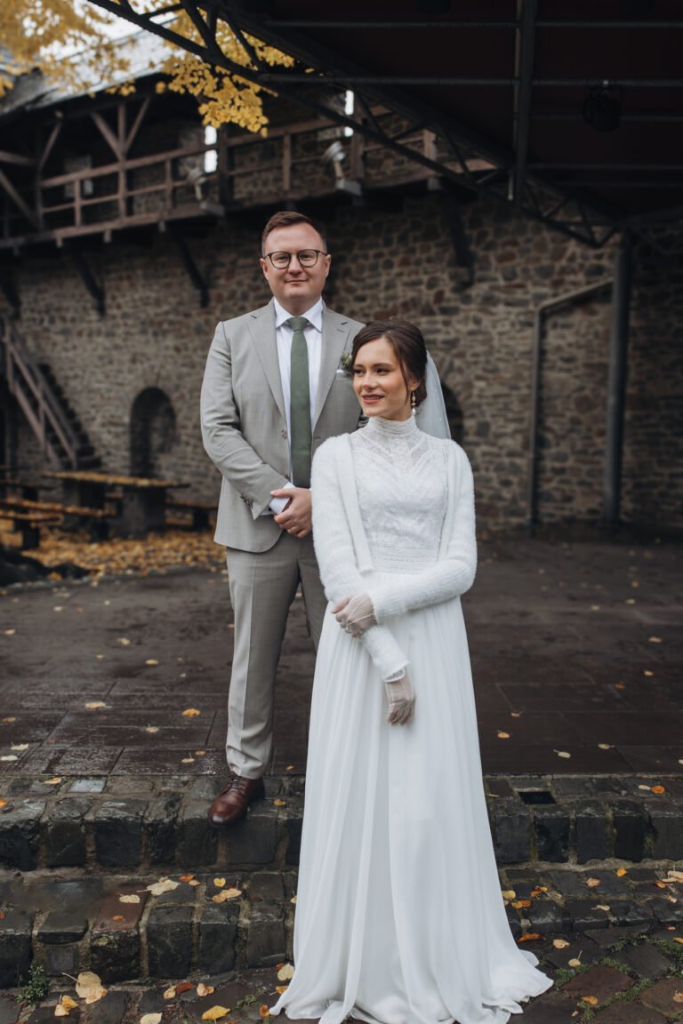 Brautpaar vor alter Burgmauer im Herbstlaub – Hochzeitsportrait