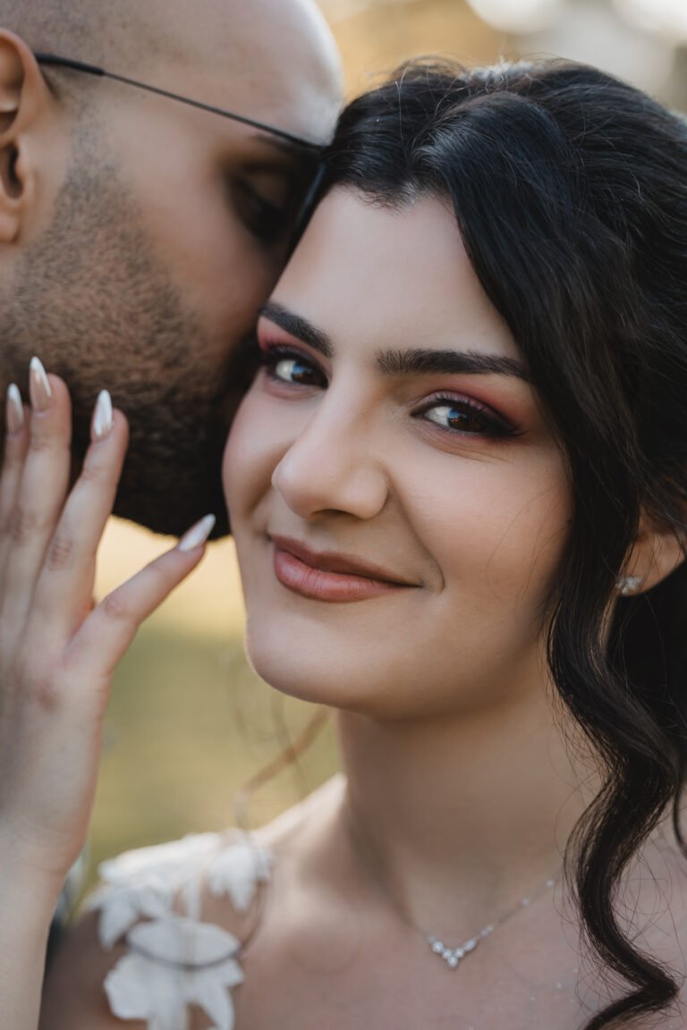 Bräutigam küsst die Braut auf die Schläfe – emotionales Hochzeitsportrait