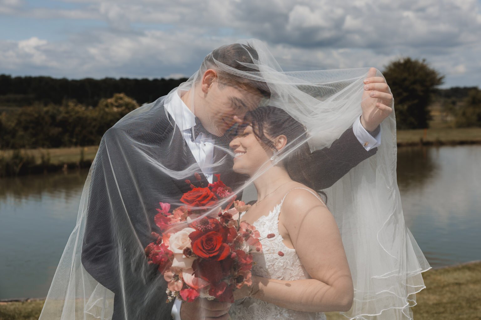 Brautpaar unter dem Brautschleier am See – After-Wedding-Aufnahme