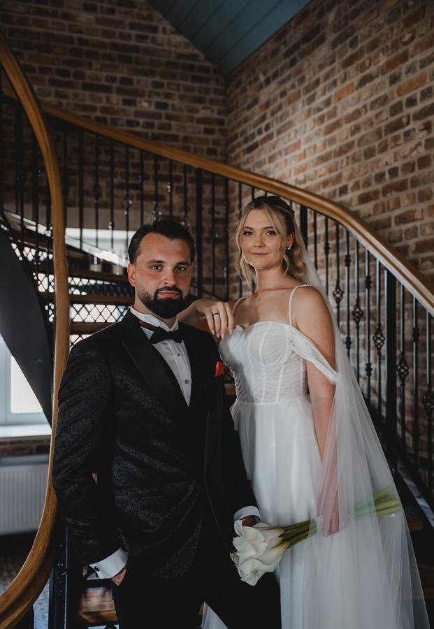 Brautpaar auf einer Treppe vor Backsteinwand – Hochzeitsportrait Industriekulisse