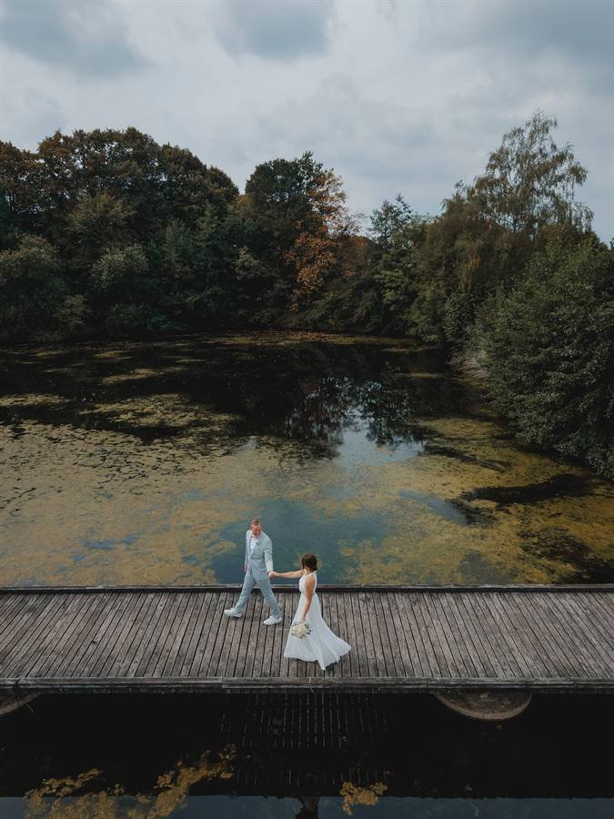 Brautpaar auf einem Steg am Waldsee von oben – Drohnenfoto beim After-Wedding-Shooting